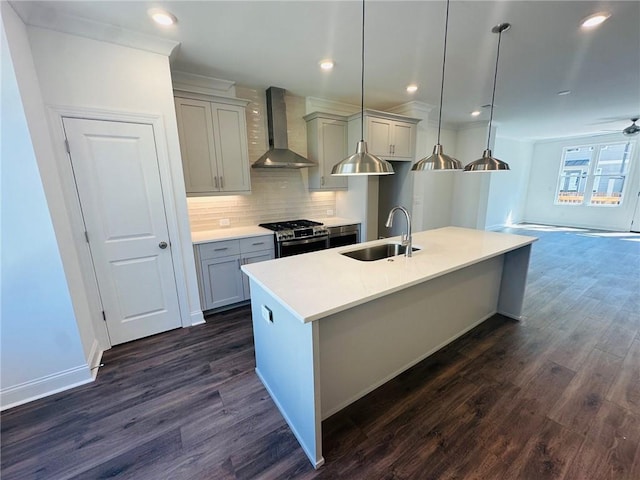 kitchen with pendant lighting, sink, stainless steel gas range, wall chimney exhaust hood, and dark hardwood / wood-style floors