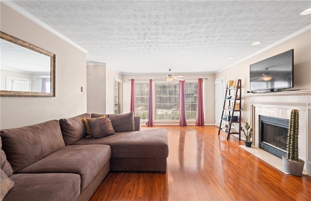 living area featuring a textured ceiling, wood finished floors, crown molding, and a tile fireplace