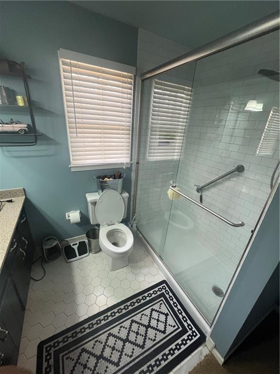 full bath with toilet, a stall shower, tile patterned flooring, baseboards, and vanity