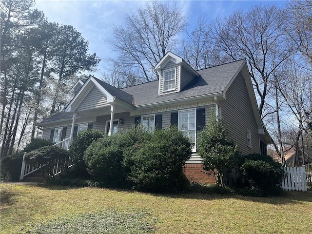 view of front of home with a front lawn, fence, and a shingled roof