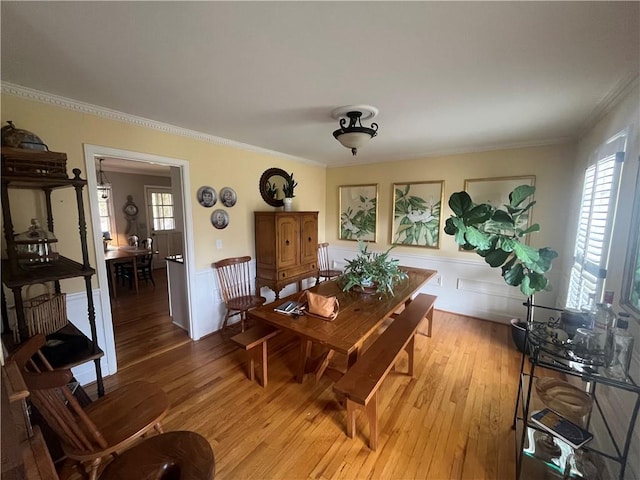 dining space featuring a wainscoted wall, plenty of natural light, light wood-style flooring, and ornamental molding