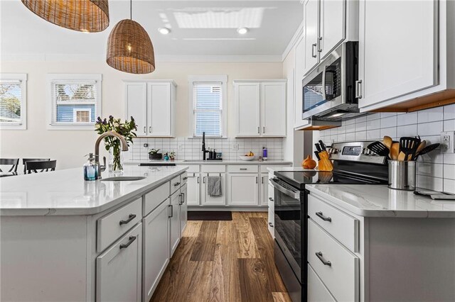 kitchen featuring white cabinetry, stainless steel appliances, a kitchen island with sink, and hanging light fixtures