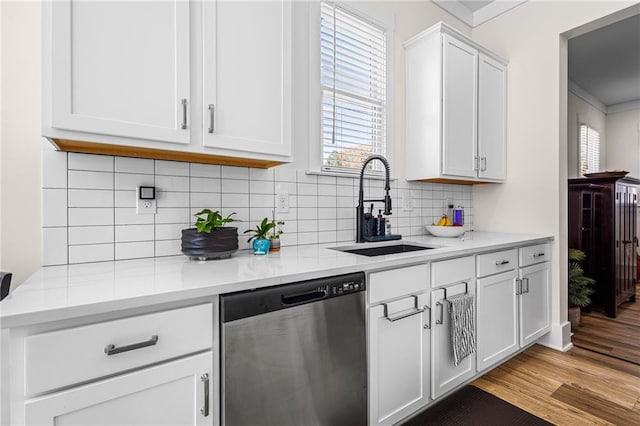 kitchen with dishwasher, sink, white cabinets, light hardwood / wood-style floors, and decorative backsplash