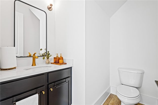 bathroom featuring vanity, toilet, hardwood / wood-style floors, and lofted ceiling