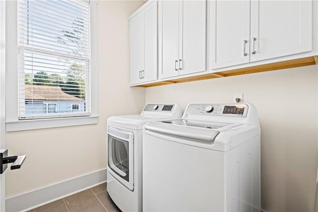 laundry room featuring washing machine and clothes dryer, cabinets, and dark tile patterned flooring