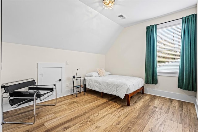 bedroom with light hardwood / wood-style floors, multiple windows, and lofted ceiling