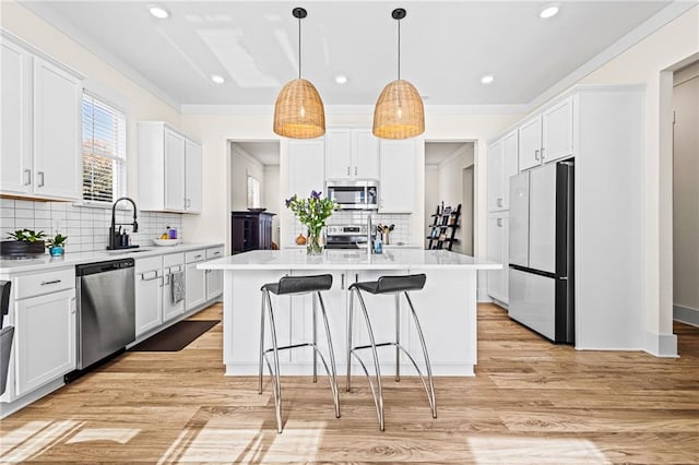 kitchen with white cabinets, a kitchen island, stainless steel appliances, light hardwood / wood-style floors, and sink