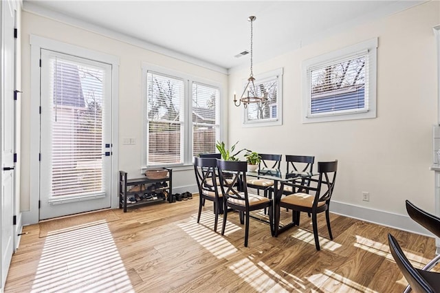 dining area with light hardwood / wood-style floors and a notable chandelier