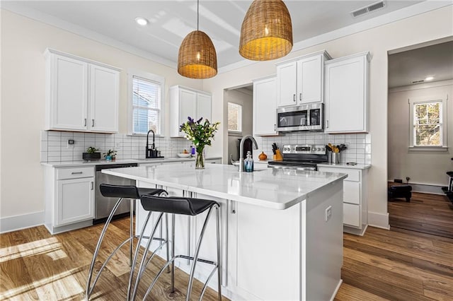 kitchen with a kitchen island, light hardwood / wood-style floors, white cabinetry, and appliances with stainless steel finishes