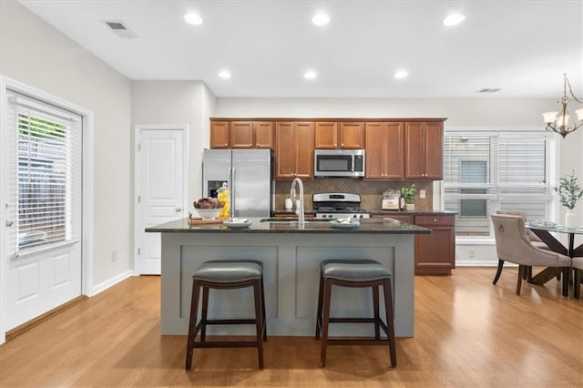 3607 Archgate Ct, Alpharetta, GA 30004 - kitchen featuring appliances with stainless steel finishes, brown cabinetry, a sink, backsplash, and light wood-type flooring