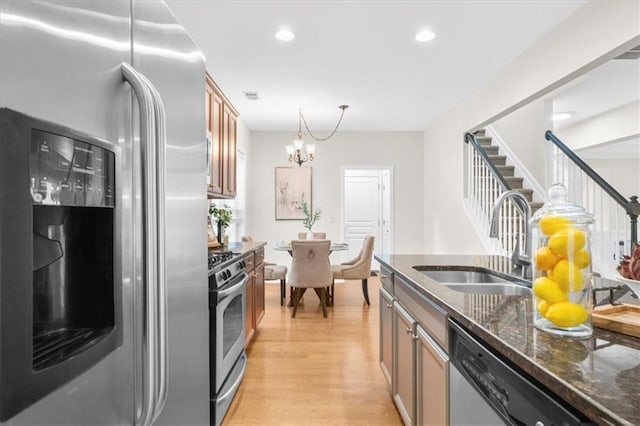 3607 Archgate Ct, Alpharetta, GA 30004 - kitchen with stainless steel appliances, a sink, light wood-style floors, dark stone counters, and a chandelier