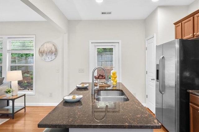 3607 Archgate Ct, Alpharetta, GA 30004 - kitchen with stainless steel fridge with ice dispenser, a sink, light wood-style flooring, a center island with sink, and dark stone countertops