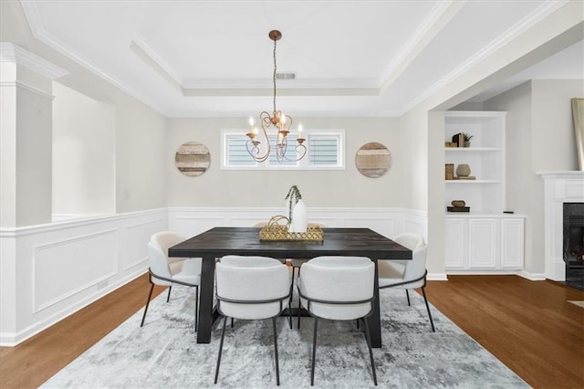 3607 Archgate Ct, Alpharetta, GA 30004 - dining area featuring wood finished floors, a chandelier, a premium fireplace, crown molding, and a raised ceiling