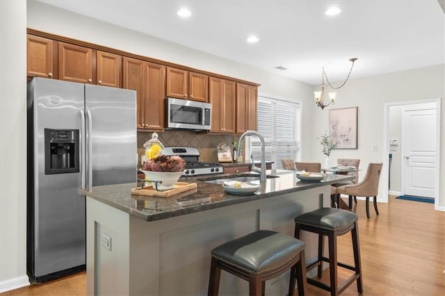 3607 Archgate Ct, Alpharetta, GA 30004 - kitchen featuring stainless steel appliances, brown cabinetry, a sink, decorative backsplash, and light wood-style floors