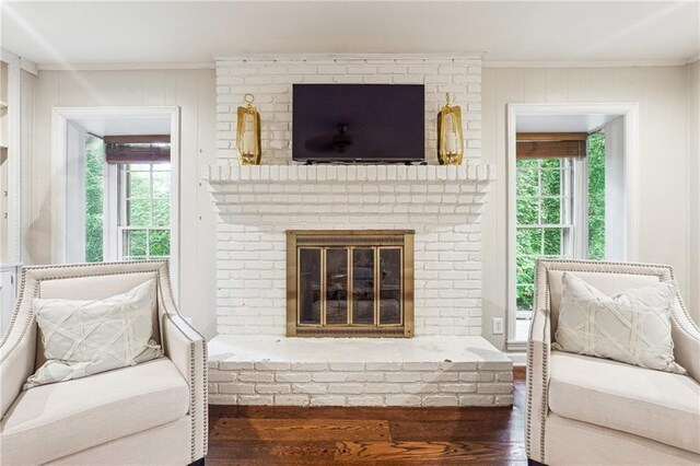 living area with a wealth of natural light, a fireplace, ornamental molding, and hardwood / wood-style flooring