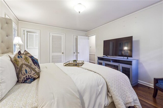 bedroom featuring hardwood / wood-style floors, crown molding, and multiple closets