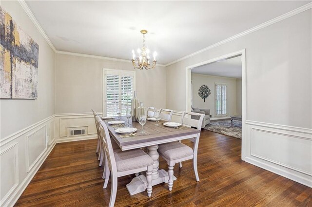 dining area with ornamental molding, dark wood-type flooring, and an inviting chandelier