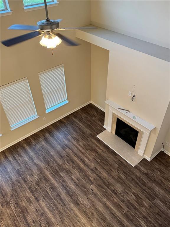 7703 Hansel Ln, Lithonia, GA 30058 - unfurnished living room with dark wood-type flooring, a ceiling fan, and a premium fireplace