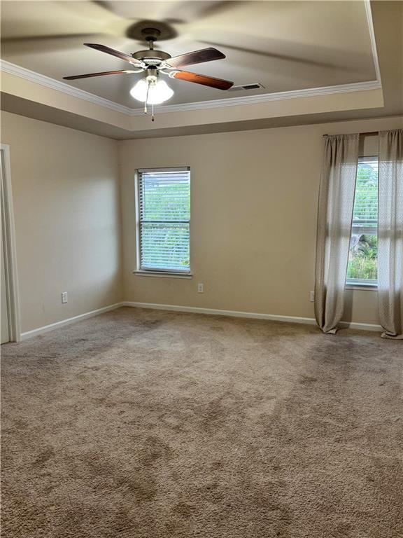7703 Hansel Ln, Lithonia, GA 30058 - unfurnished room featuring a tray ceiling, ornamental molding, plenty of natural light, carpet, and a ceiling fan
