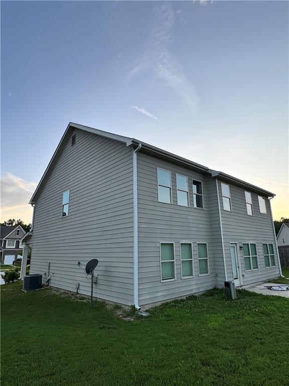 7703 Hansel Ln, Lithonia, GA 30058 - view of property exterior featuring a central AC unit and a lawn