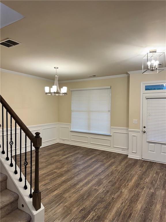 7703 Hansel Ln, Lithonia, GA 30058 - entryway featuring a chandelier, a decorative wall, dark wood-style floors, crown molding, and wainscoting