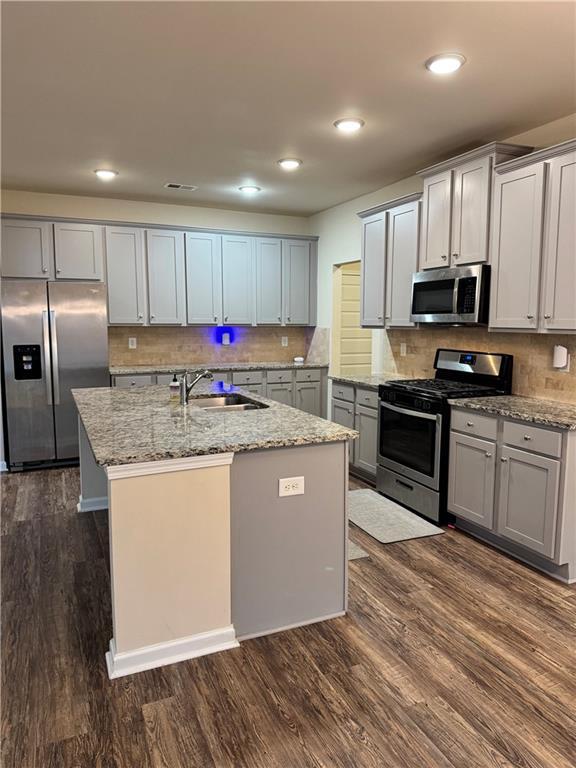 7703 Hansel Ln, Lithonia, GA 30058 - kitchen featuring stainless steel appliances, dark wood-style floors, a center island with sink, backsplash, and recessed lighting