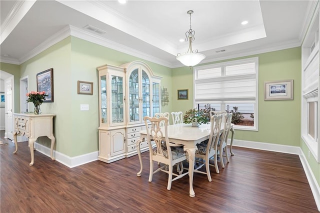 dining area featuring dark hardwood / wood-style flooring, crown molding, and a tray ceiling