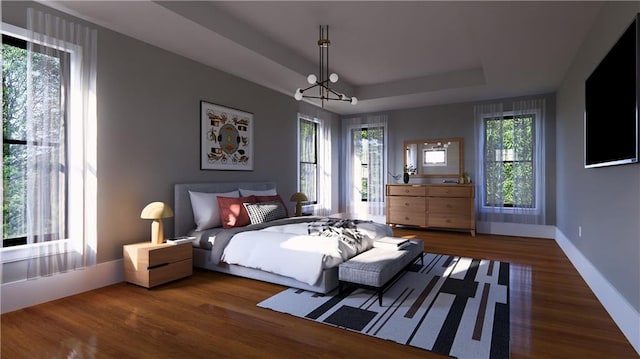 bedroom featuring a notable chandelier, a tray ceiling, and dark hardwood / wood-style floors