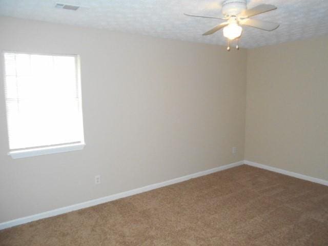 carpeted empty room with ceiling fan, baseboards, and a textured ceiling