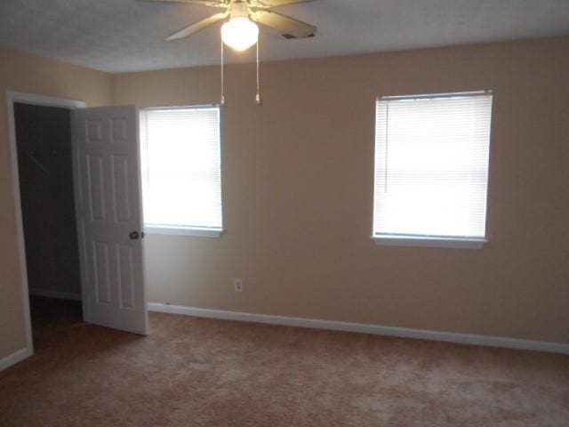 empty room featuring light carpet, ceiling fan, and baseboards