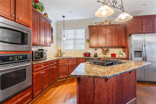 kitchen featuring pendant lighting, light wood-type flooring, stainless steel appliances, and crown molding