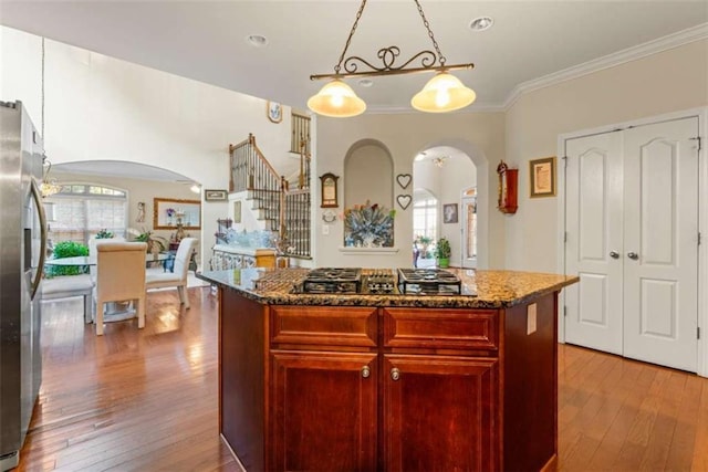 kitchen featuring hanging light fixtures, a kitchen island, light wood-type flooring, and appliances with stainless steel finishes