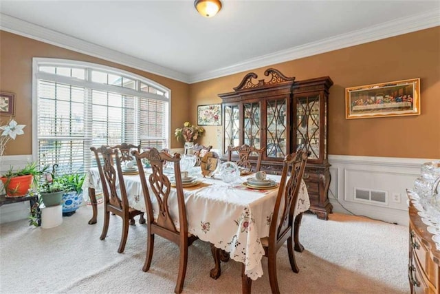 carpeted dining room with ornamental molding