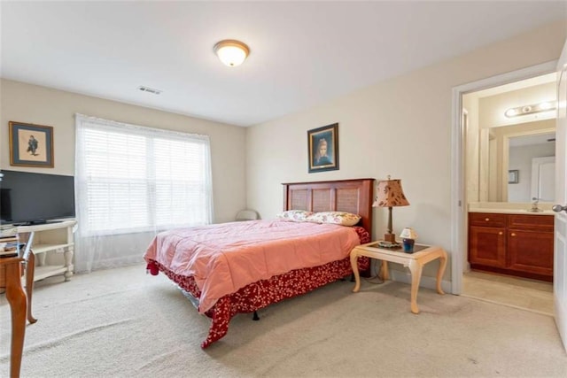 bedroom with connected bathroom and light colored carpet