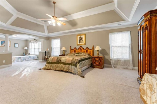 carpeted bedroom with a tray ceiling, ornate columns, ceiling fan, and ornamental molding