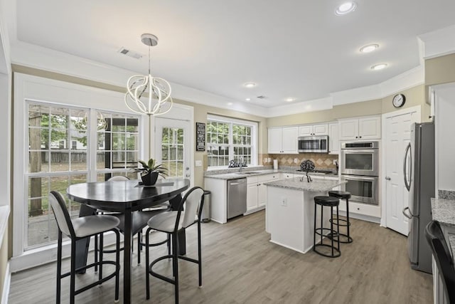 1465 Laleiah Dr, Cumming, GA 30041 - kitchen featuring crown molding, white cabinets, a notable chandelier, appliances with stainless steel finishes, and visible vents