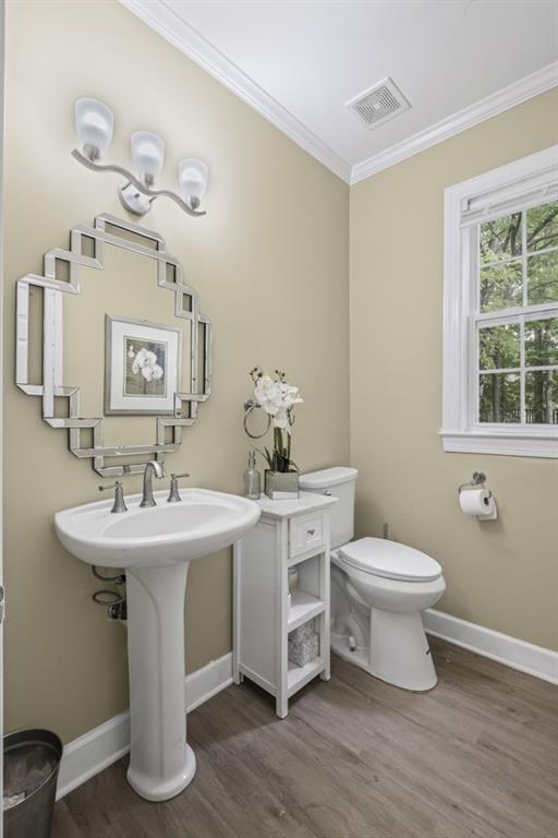 1465 Laleiah Dr, Cumming, GA 30041 - half bathroom featuring visible vents, crown molding, wood finished floors, toilet, and baseboards