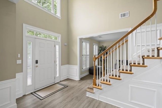 1465 Laleiah Dr, Cumming, GA 30041 - entryway with visible vents, a towering ceiling, wainscoting, wood finished floors, and a decorative wall