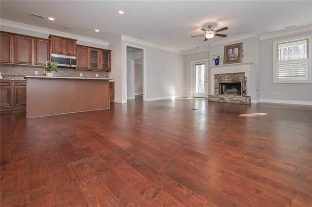 unfurnished living room with a healthy amount of sunlight, dark wood-type flooring, and a fireplace