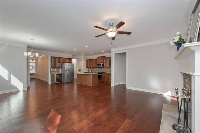 unfurnished living room with ornamental molding, a stone fireplace, ceiling fan with notable chandelier, and dark hardwood / wood-style flooring