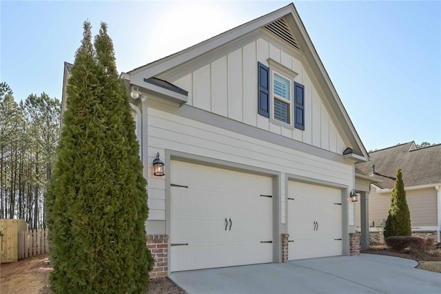 view of home's exterior featuring board and batten siding, driveway, a garage, and fence