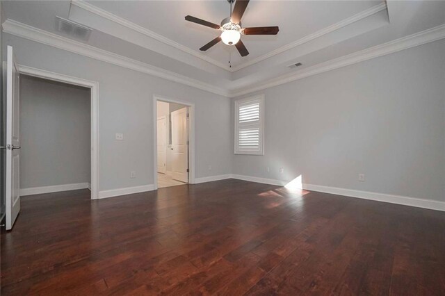 unfurnished bedroom featuring dark wood-type flooring, ceiling fan, ornamental molding, and a tray ceiling