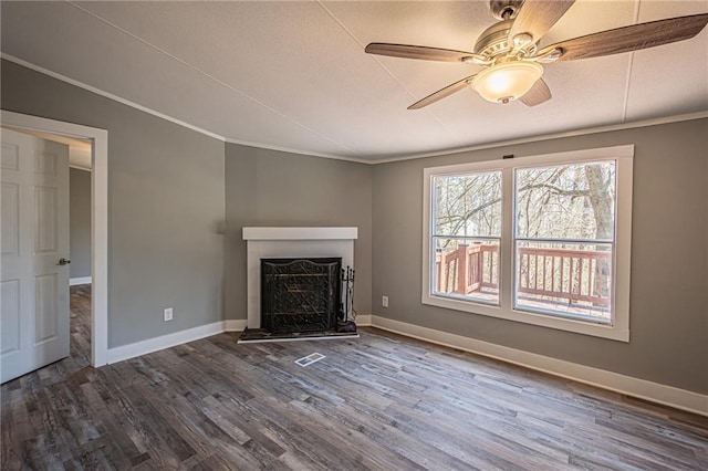 unfurnished living room with a fireplace with raised hearth, dark wood-type flooring, ceiling fan, baseboards, and ornamental molding