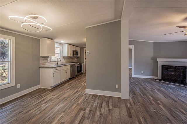 kitchen featuring a sink, tasteful backsplash, open floor plan, white cabinetry, and appliances with stainless steel finishes