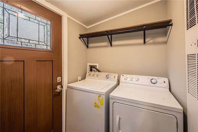 clothes washing area featuring a textured ceiling, washing machine and dryer, laundry area, and crown molding