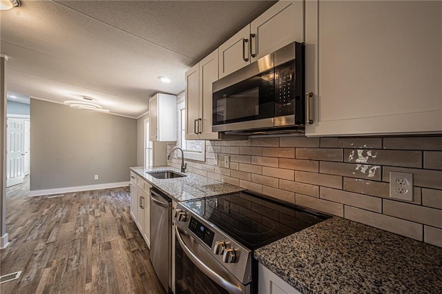 kitchen with a sink, dark stone countertops, white cabinetry, and stainless steel appliances