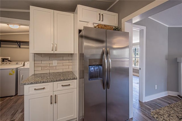 kitchen with washing machine and clothes dryer, backsplash, dark wood finished floors, dark stone countertops, and stainless steel fridge