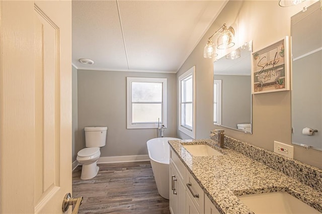 full bath featuring crown molding, baseboards, wood finished floors, a freestanding tub, and a sink