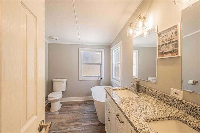 full bath with a sink, wood finished floors, double vanity, baseboards, and a soaking tub