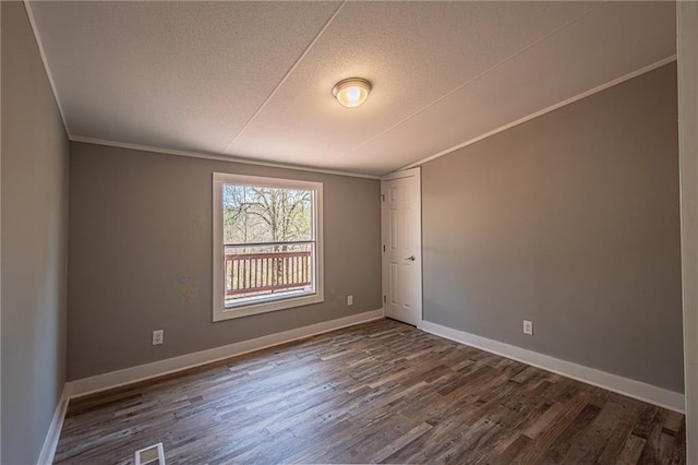 unfurnished room featuring dark wood finished floors, a textured ceiling, baseboards, and ornamental molding